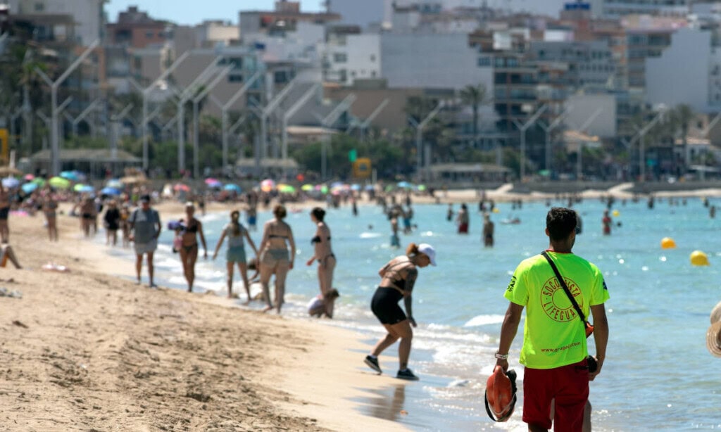 Menschen am Strand mit Stadt im Hintergrund, sonniger Tag, Urlaubsthema.