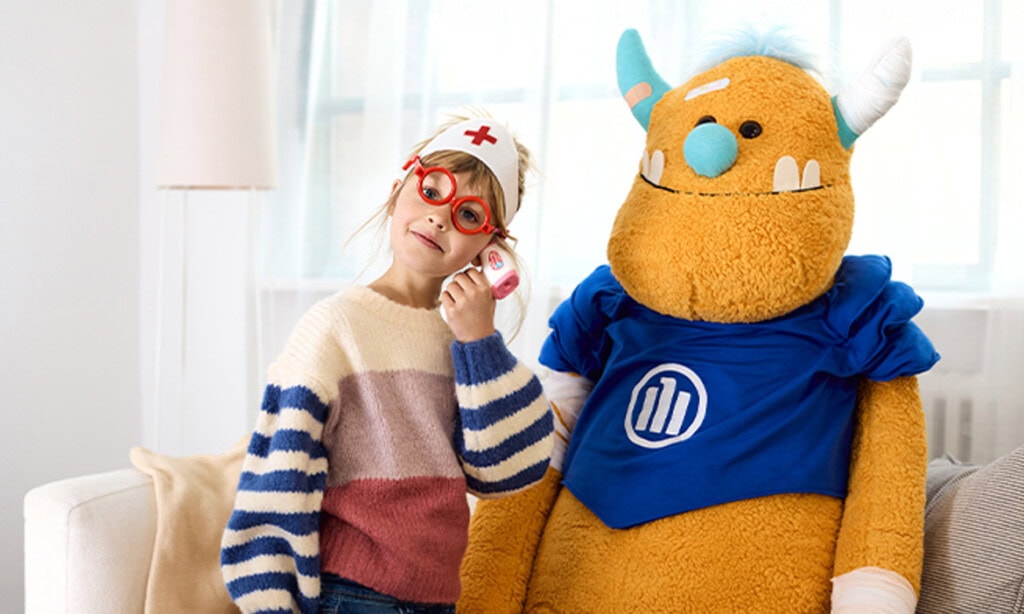 Kind mit Maskottchen bei Gesundheits- und Vorsorgeveranstaltung.