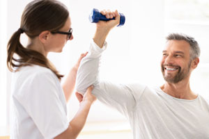 Frau trainiert mit Personal Trainer und Hantel im Fitnessstudio.