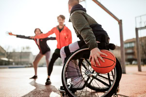 Rollstuhlfahrer spielt Basketball im Freien.