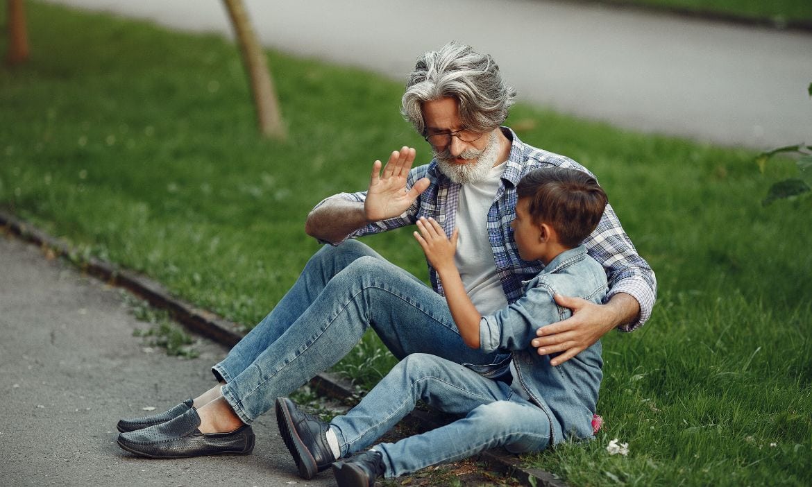Vater und Sohn spielen lachend im Park auf der Wiese.