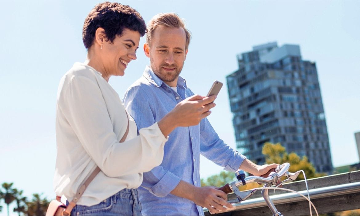 Zwei Personen schauen auf ein Smartphone während des Fahrradfahrens.