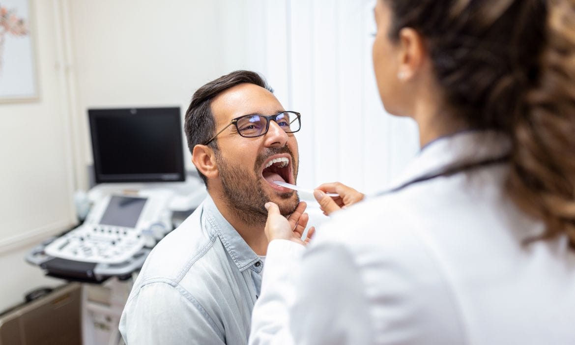 Ein HNO-Arzt untersucht den Rachen eines Patienten.