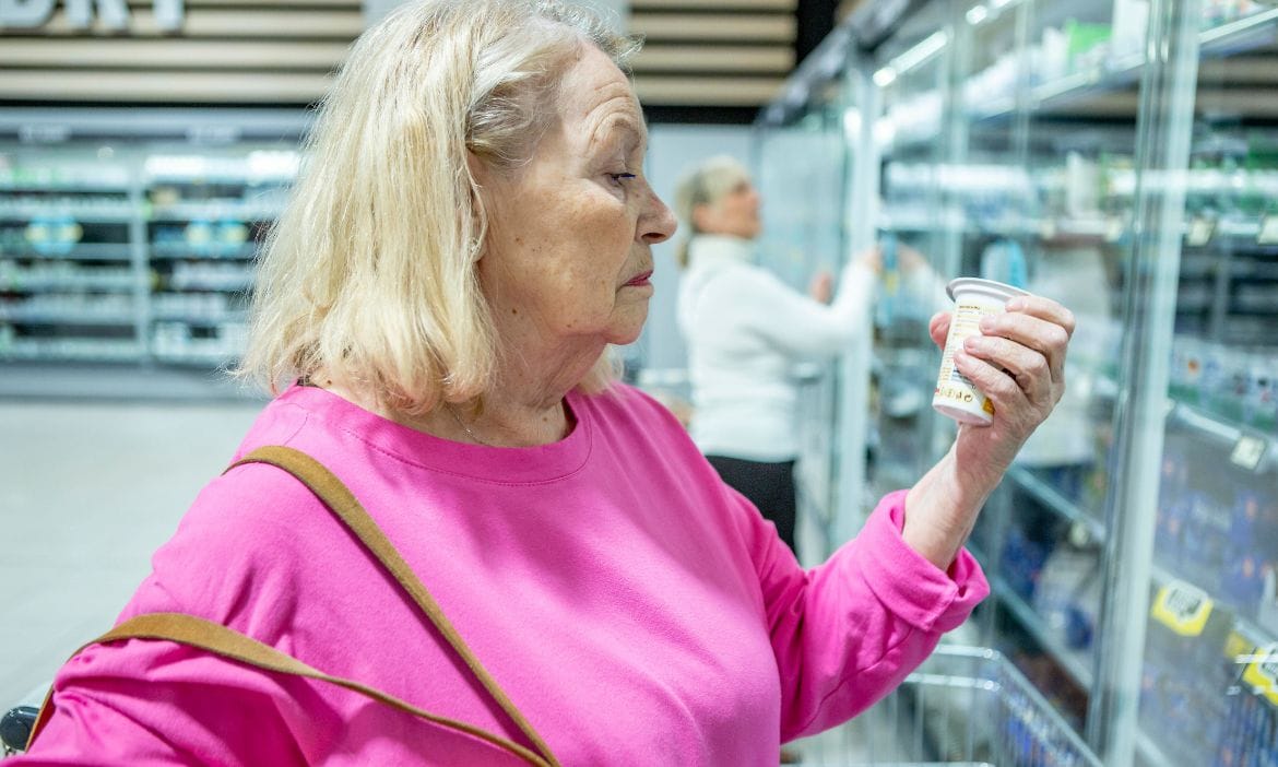 Eine Seniorin schaut im Supermarkt besorgt auf die Preise.
