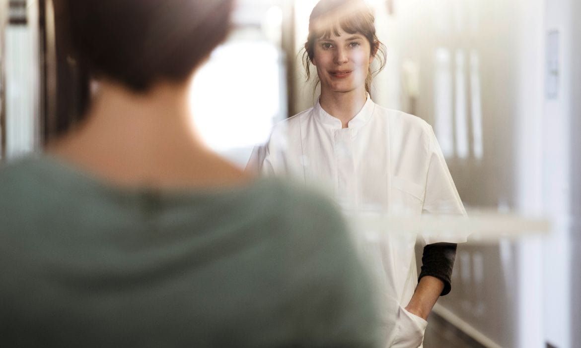 Pflegekraft spricht mit Patientin in einem Pflegeheim.