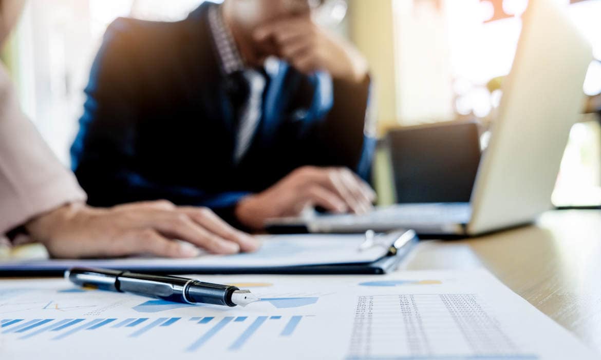 Geschäftsmann bei Finanzplanung mit Laptop und Dokumenten.