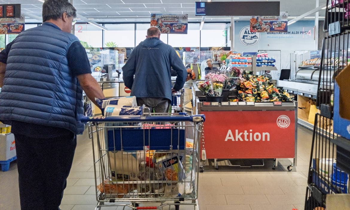 Deutsche Kunden beim Einkaufen im Supermarkt mit Einkaufswagen.