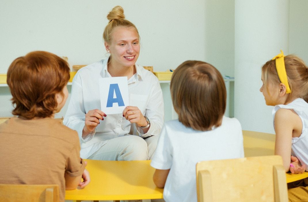 Lehrerin zeigt Kindern den Buchstaben A im Klassenzimmer.
