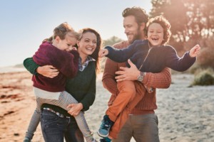 Familie beim Spielen am Strand bei Sonnenuntergang.