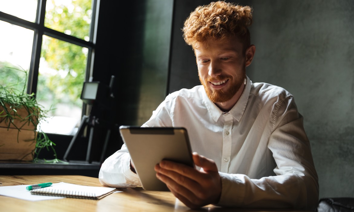 Mann mit Tablet: In Deutschland hat mehr als die Hälfte der Befragten KI-Anwendungen bereits für Finanz- oder Versicherungsthemen genutzt.